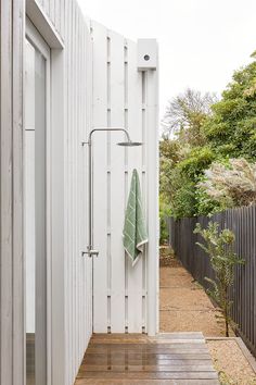 an outdoor shower in the middle of a wooden decked area next to a white building