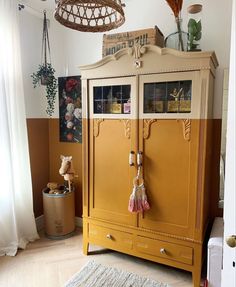 a yellow cabinet sitting in the corner of a room next to a rug and window