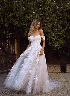 a woman in a white wedding dress standing outside