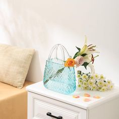 a blue bag sitting on top of a white table next to a bed with pillows