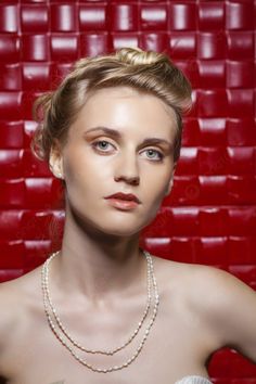 a woman in a white dress is posing for the camera with pearls on her necklace