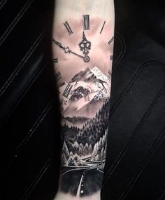 a man's arm with a clock and mountain scene on the inside of it