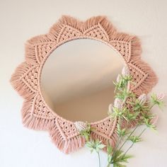 a round mirror hanging on the wall next to a plant