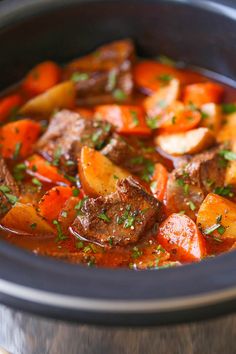 a stew with carrots, potatoes and meat in a slow cooked crock pot