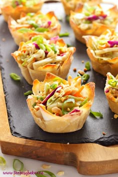 small cups filled with food sitting on top of a wooden tray