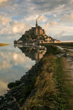 an island with a castle on top is reflected in the water