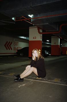 a woman sitting on the ground in a parking garage