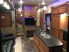 a kitchen and living room in an rv with dark wood cabinets, black counter tops, and stainless steel appliances