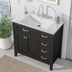 a bathroom sink sitting under a mirror next to a potted plant