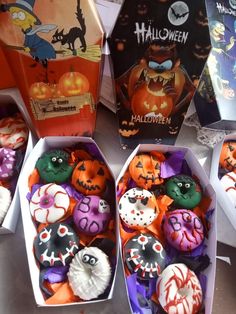 several decorated cupcakes in boxes on a table with other halloween treats and decorations