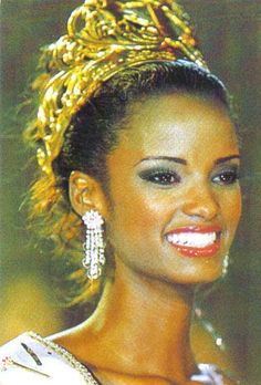 a woman wearing a tiara and smiling at the camera with gold jewelry on her head