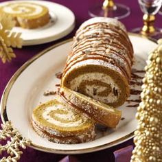 a plate topped with a roll covered in powdered sugar next to a christmas tree