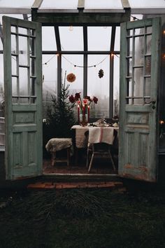 an open door to a dining room with christmas decorations on the table and lights hanging from the ceiling