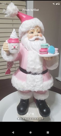 a santa clause figurine holding a cupcake on a plate with other decorations