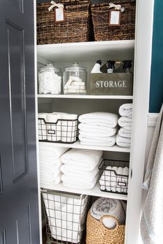 an organized closet with baskets and towels