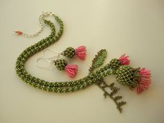 a green and pink beaded necklace with matching earring set on a white surface