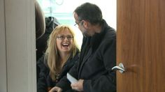 the man and woman are laughing as they look at each other through the door handle