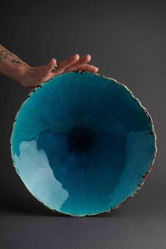 a person's hand holding a large blue bowl