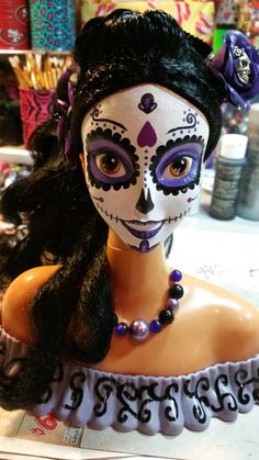 a woman's face painted in white and black with purple flowers on her head