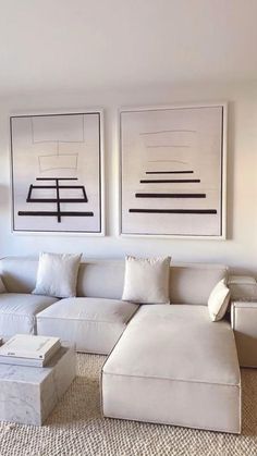 a living room filled with white furniture and art on the wall above it's fireplace