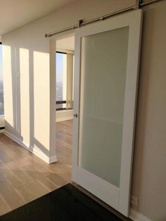 an empty room with sliding glass doors and hardwood flooring, overlooking the city skyline