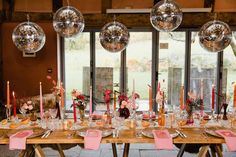 a long table is set with pink napkins and place settings in front of large windows