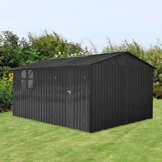 a black shed sitting on top of a lush green field