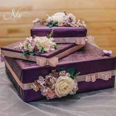 three purple boxes with flowers on them sitting on a table