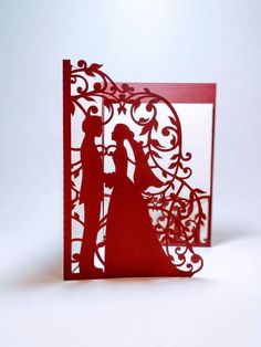 a red laser cut card with a silhouette of a bride and groom