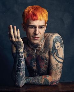 a man with red hair and tattoos sitting at a table