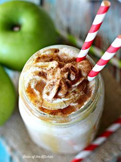 there is an apple and cinnamon drink with two straws on the table next to it