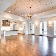 an empty living room with wood floors and chandelier