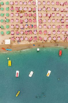 an aerial view of the beach with many umbrellas and boats in the water next to it