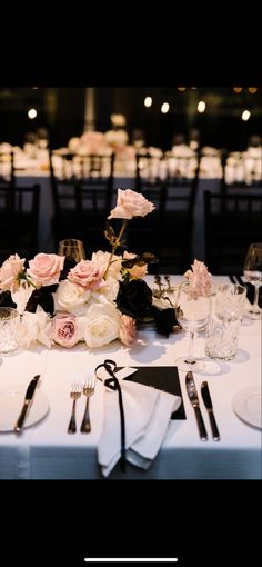 the table is set with white and pink flowers, silverware, and napkins