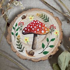 a red mushroom sitting on top of a piece of wood next to flowers and leaves