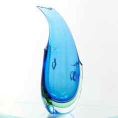 a blue glass vase sitting on top of a white table next to a green plant