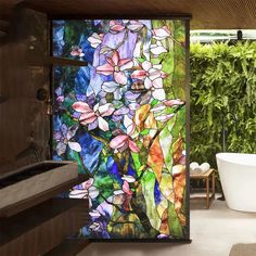 a bath tub sitting next to a window covered in stained glass flowers and leaves on the wall