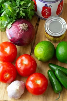 tomatoes, limes, onions, and other vegetables on a cutting board next to a can of yogurt