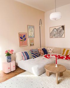 a living room filled with white furniture and lots of pictures on the wall above it