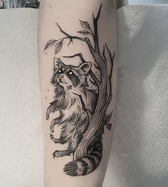 a black and white tattoo of a raccoon sitting on a tree branch with leaves