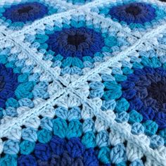 a blue and white crocheted blanket is laying on the floor