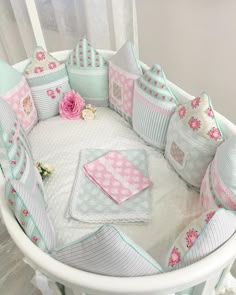 a baby crib with pink and blue pillows on it's sides, along with other items