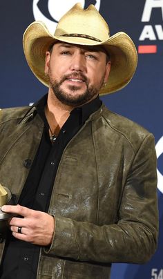 a man wearing a cowboy hat and leather jacket holding an award in his right hand