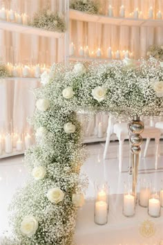 white flowers and candles are arranged on the floor in front of a wedding ceremony arch