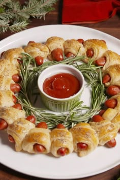 a white plate topped with pigs in a blanket next to a bowl of ketchup