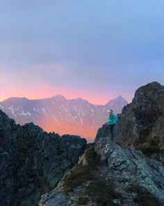 a person standing on top of a mountain with mountains in the background at sunset or dawn