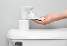 a person is cleaning the toilet with a tissue dispenser