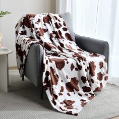 a living room with a couch and chair covered in a brown and white cow print blanket