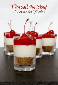 four small desserts with cherries and cheesecake shots in glass cups on a table