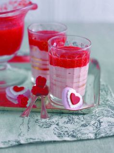 two glasses filled with red liquid sitting next to each other on a tablecloth covered tray